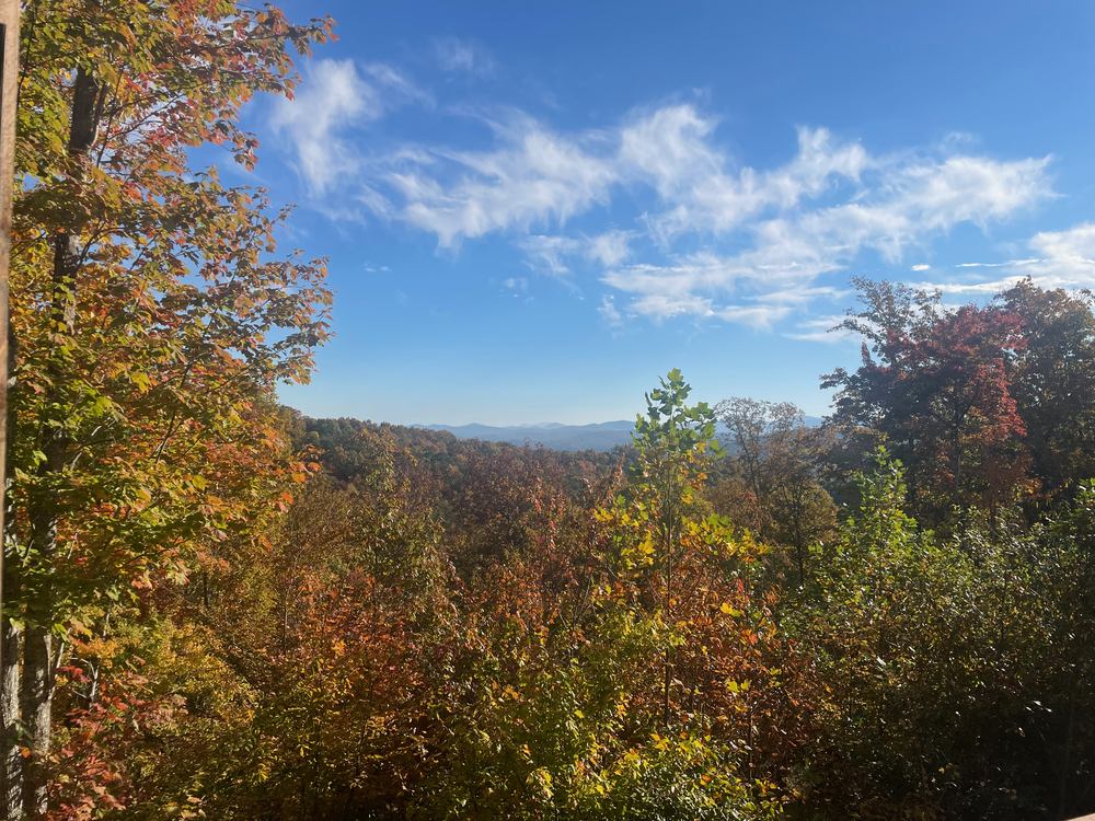 Peak October fall color and distant blue ridgelines seen from a cabin porch near Blue Ridge, Georgia