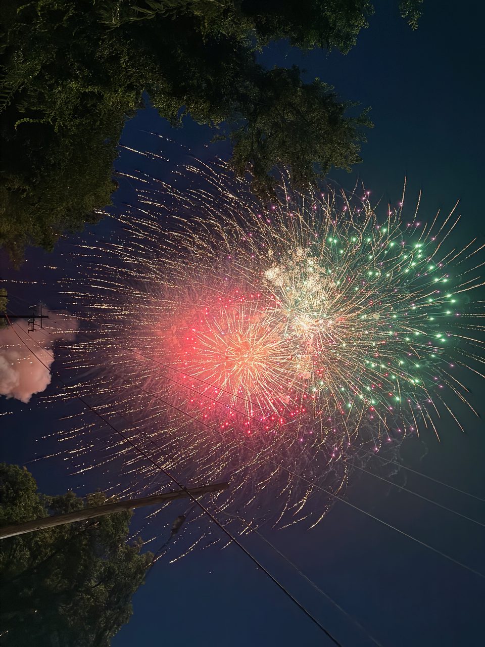 Multiple fireworks bursting at once in red, green, and white over Hahira