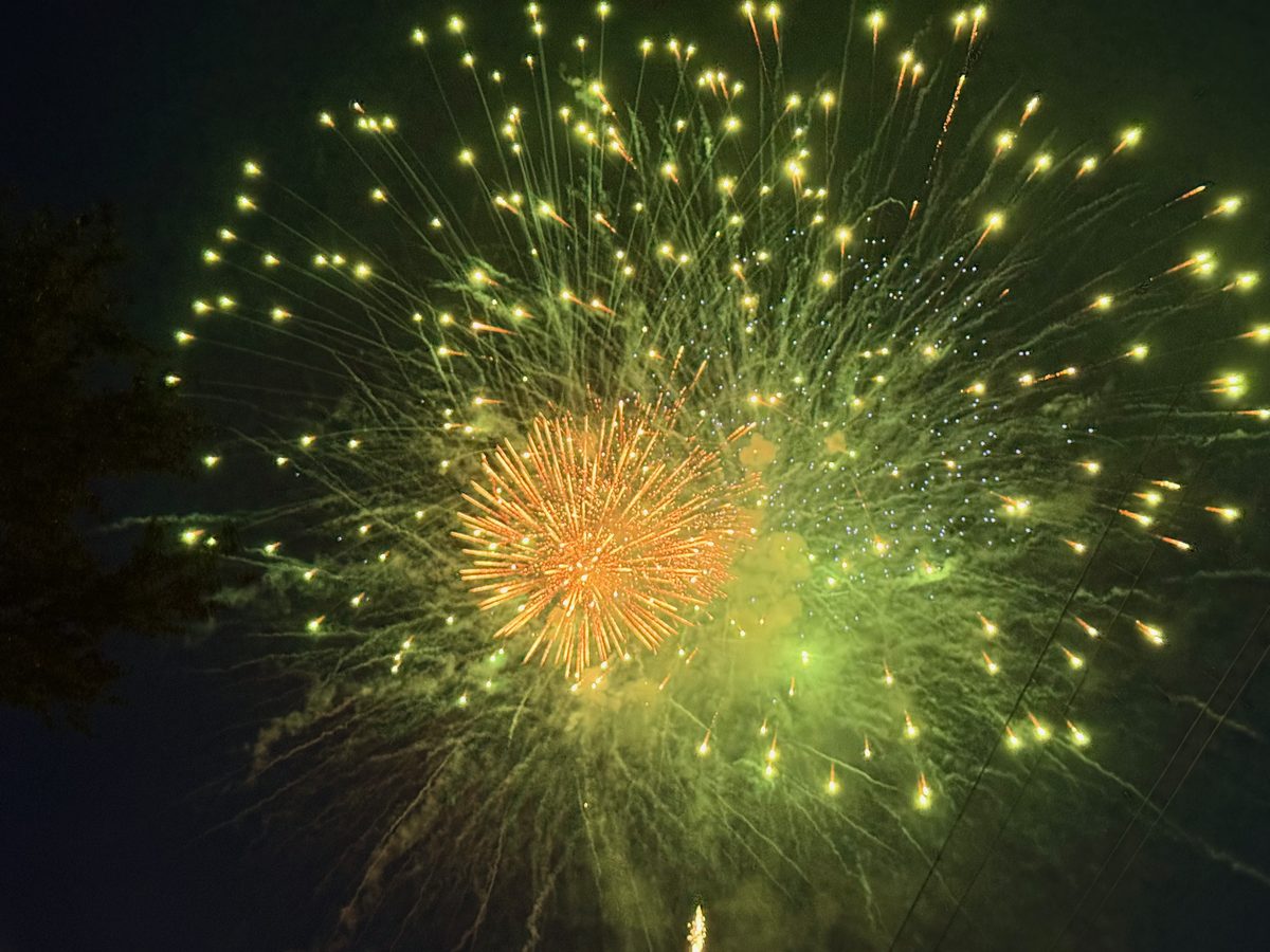 A finale of many fireworks bursting together, filling the sky with red, green, and gold