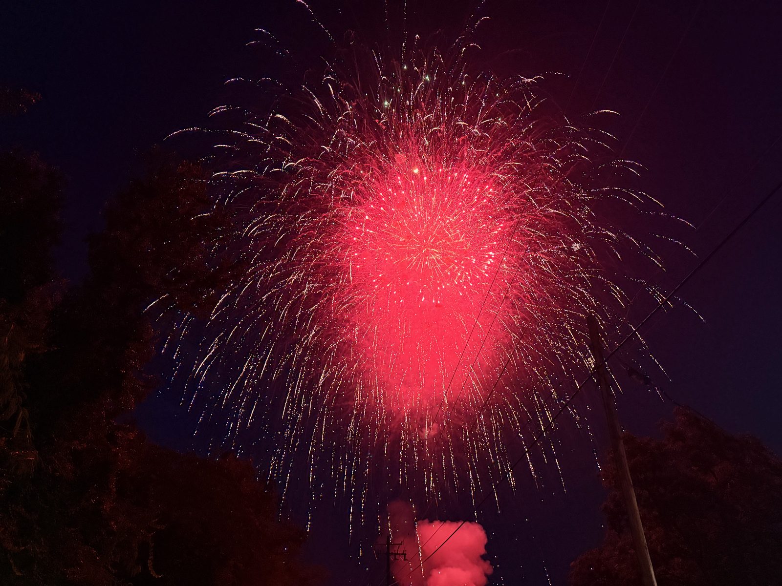 A large red firework bursting and raining gold sparks over Hahira, Georgia